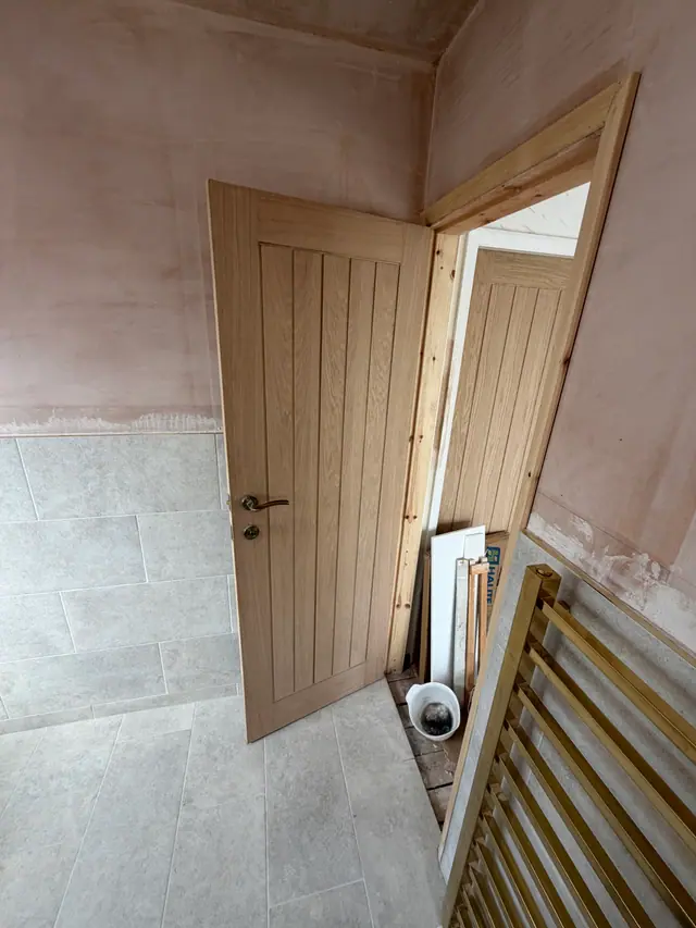 Bathroom finishing work in progress with new door and floor tiling