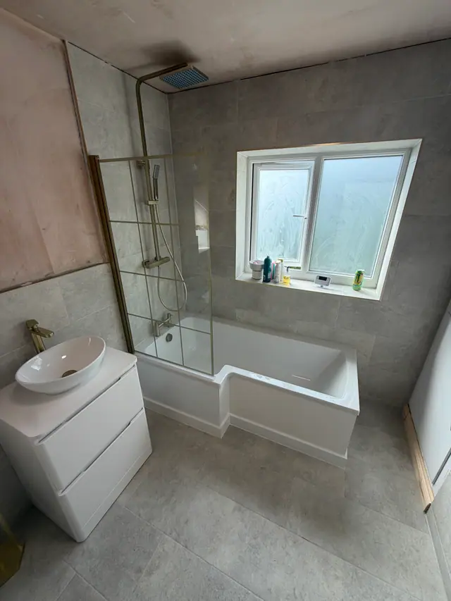 Bathroom renovation in progress with bath, shower screen and stone-effect tiles