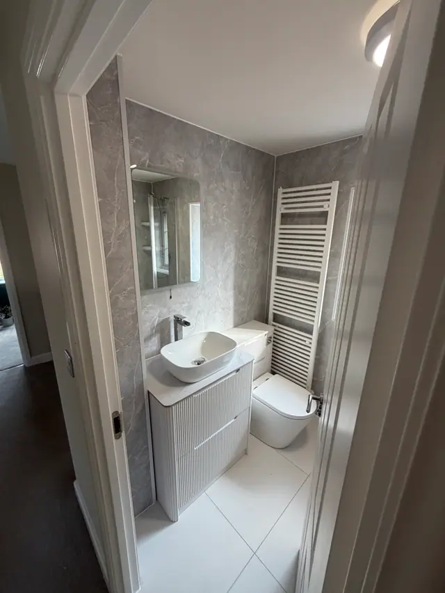 Compact cloakroom with fluted vanity and full-height grey wall panels