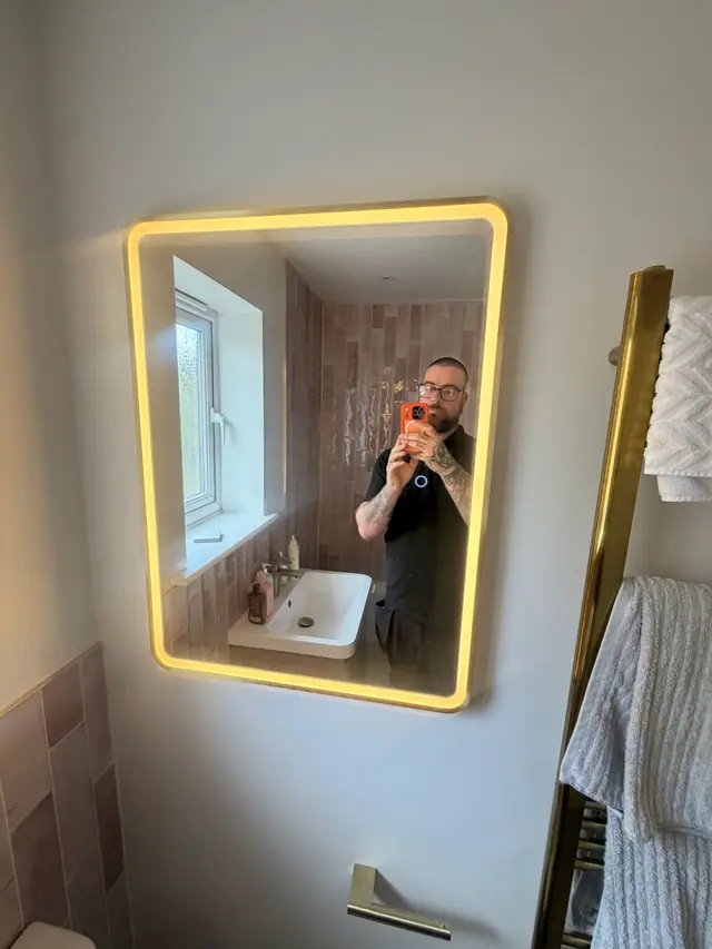 Gareth documenting a completed bathroom with an illuminated mirror