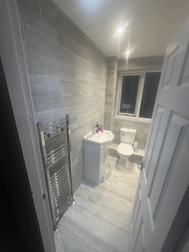 Completed grey bathroom with vanity, toilet and chrome towel rail