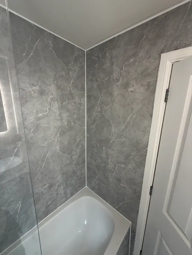 Cleanly finished grey wall panels above a white bath