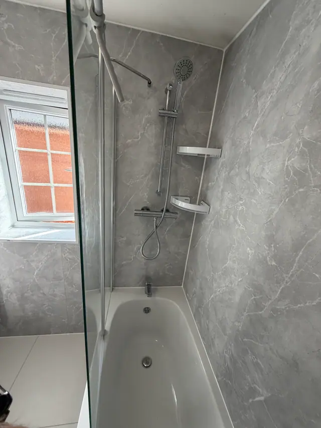 Bath and shower lined with large-format grey wall panels