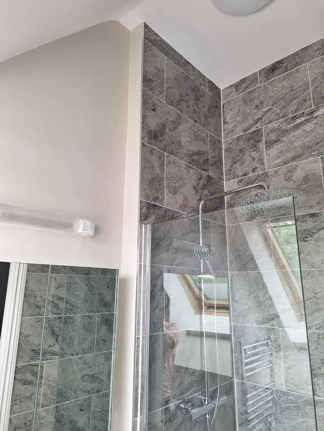 Stone-effect tiled shower fitted beneath a sloping loft ceiling