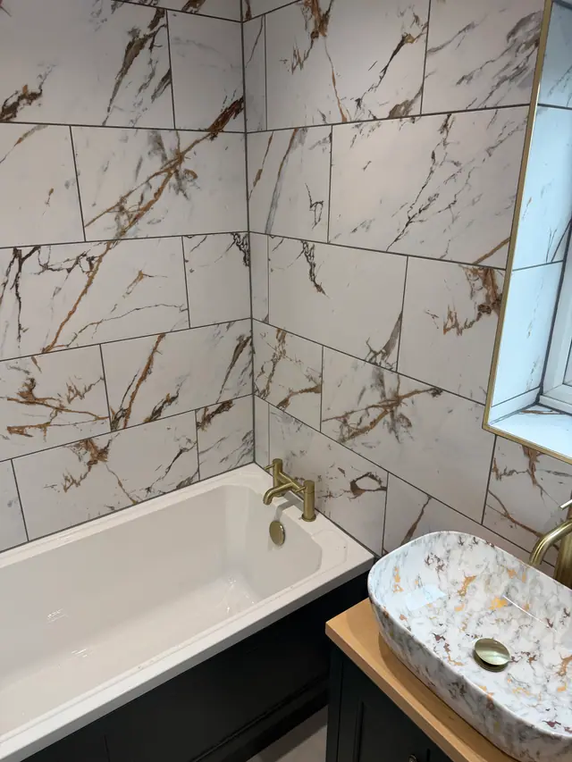 Marble-effect bath surround with coordinated basin and brushed gold fittings