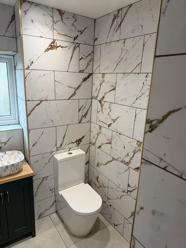 Marble-effect tiled bathroom with dark vanity and gold detailing