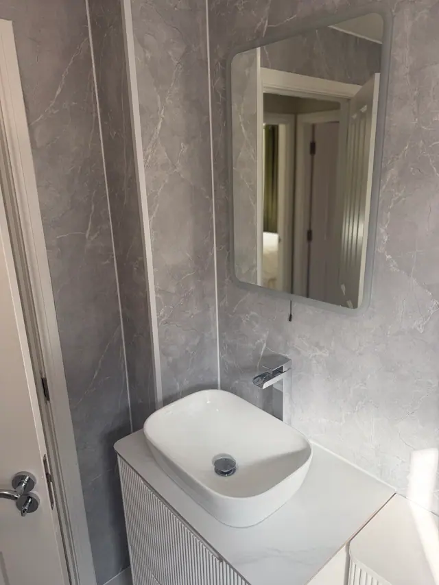 Contemporary basin and mirror against large-format grey wall panels
