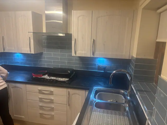Kitchen worktop and blue-grey tiled splashback with under-cabinet lighting